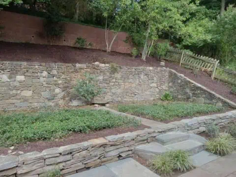 Lush landscaped backyard with stone retaining wall and tiered garden for outdoor relaxation.